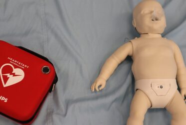 Infant CPR training manikin with AED HeartStart case for choking response