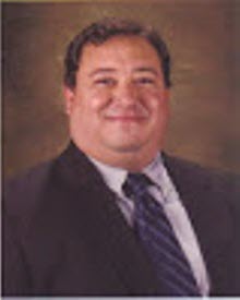 Henry Serrano, lead trainer, professional portrait in suit and striped tie